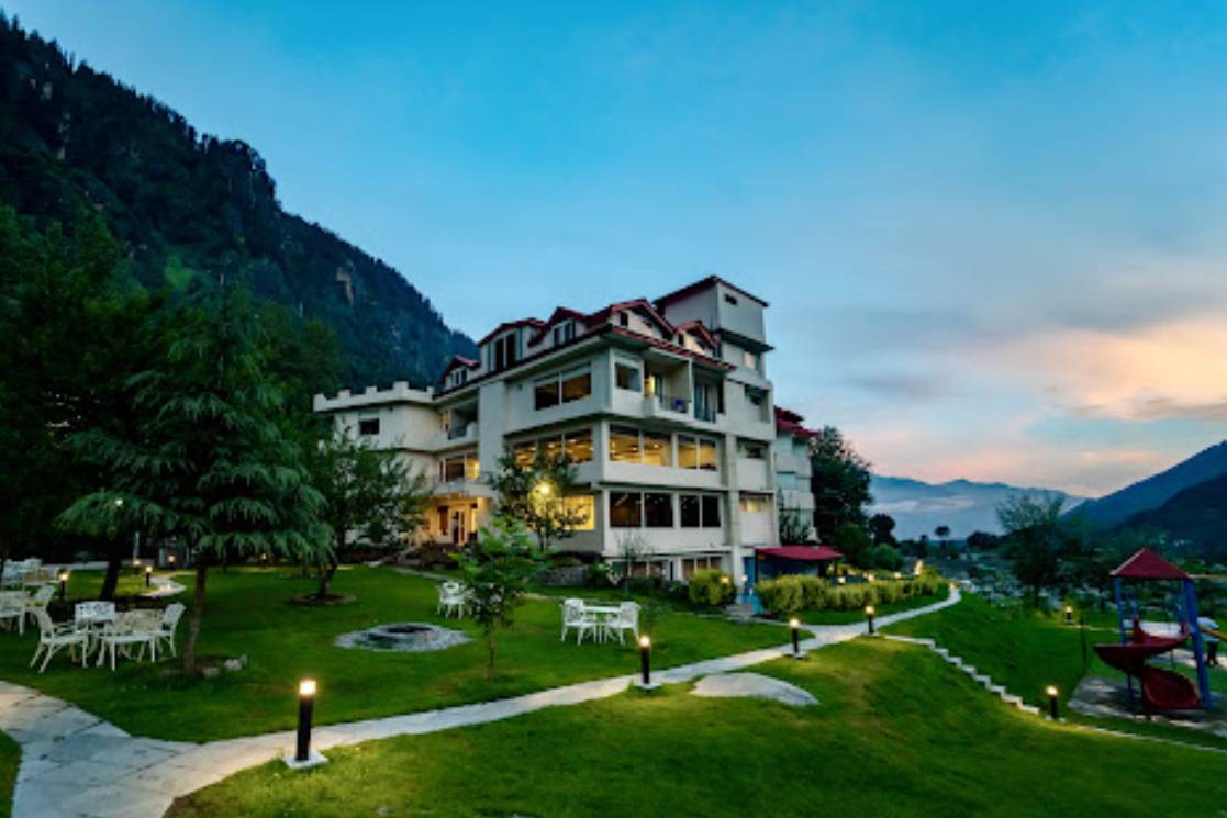 Description: A premium riverside 4-star resort located on the highway leading toward Solang Valley. It features elegant rooms with private balconies that offer direct views of the Beas River and the surrounding pine-covered mountains. The property is known for its serene ambiance, a luxury spa, and a multi-cuisine restaurant that serves fresh local trout and international dishes. Its strategic location minimizes travel time for early morning adventure activities in Solang.
