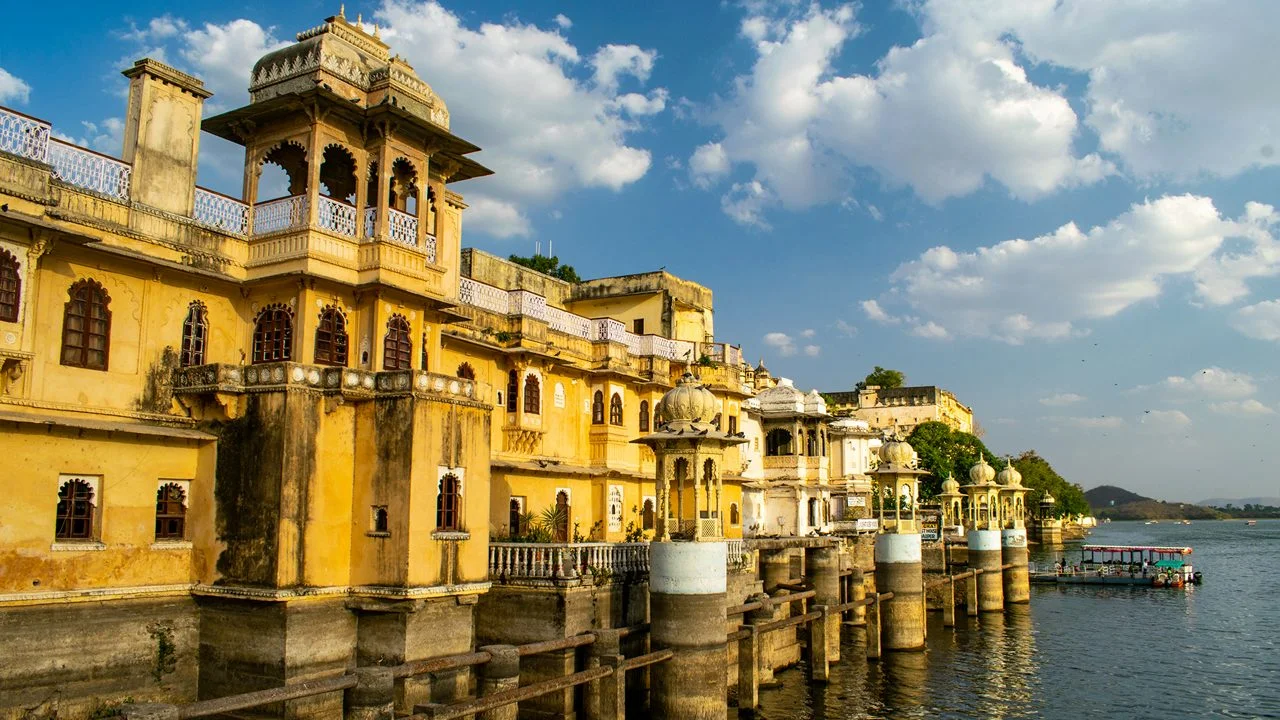 You will stay in a Heritage Haveli (like Jagat Niwas). These rooms feature Jharokhas (window seats) overlooking Lake Pichola, traditional Mewari frescoes, and antique furniture.